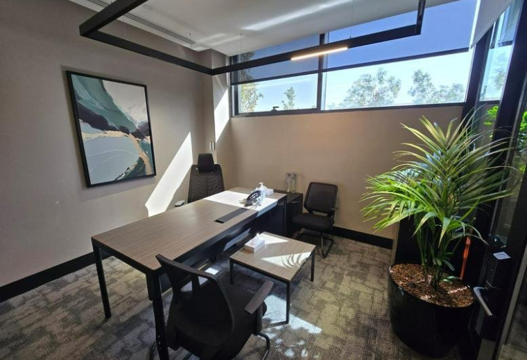 Bright private executive office at Althalia Rd, Almathar Alshimali with desk and landscape art.