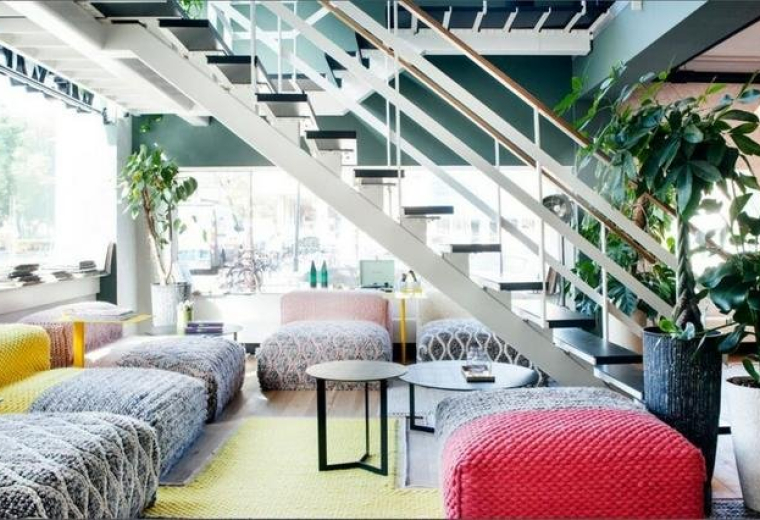 Spacious communal lounge at Arekere Village, Begur Hobli Bannerghatta Road featuring colorful poufs and a staircase.