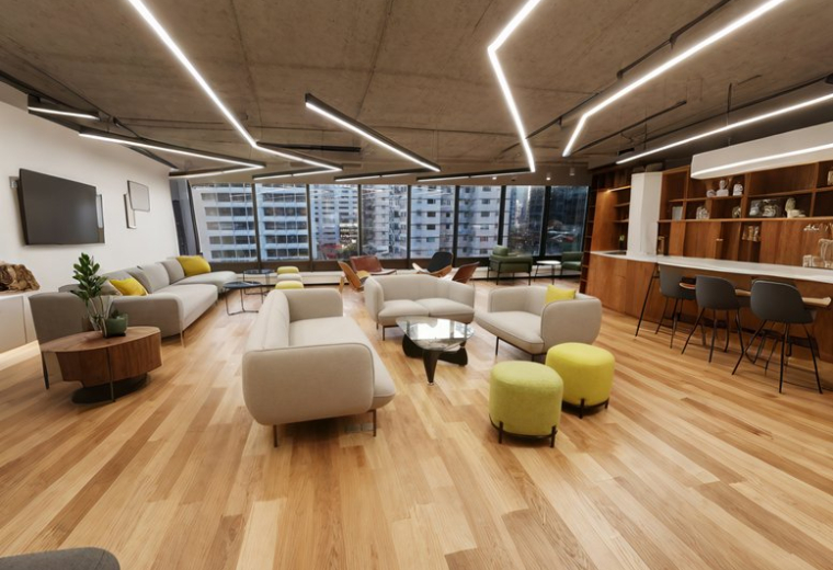 Large modern lounge with diverse seating, wooden floors, and geometric ceiling lights.