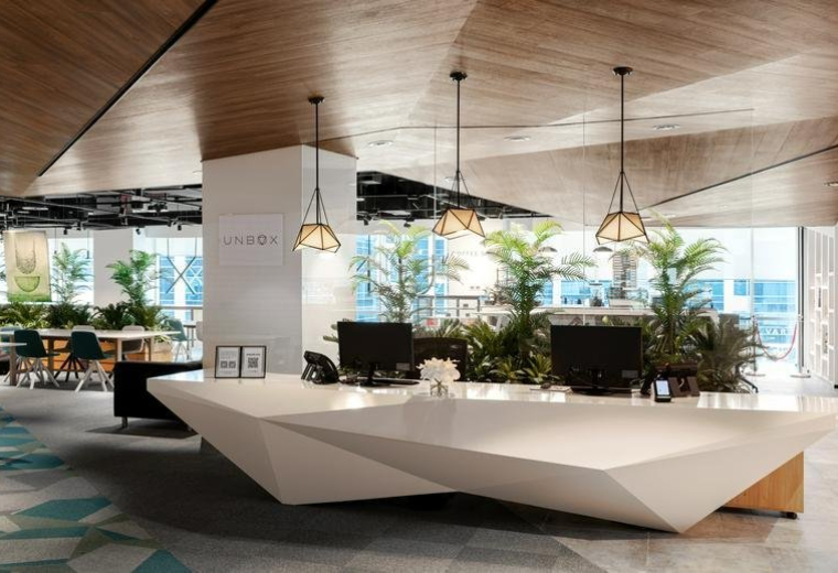 Bright reception area of Building 4, 2nd Floor featuring a geometric white desk and warm wood ceilings.