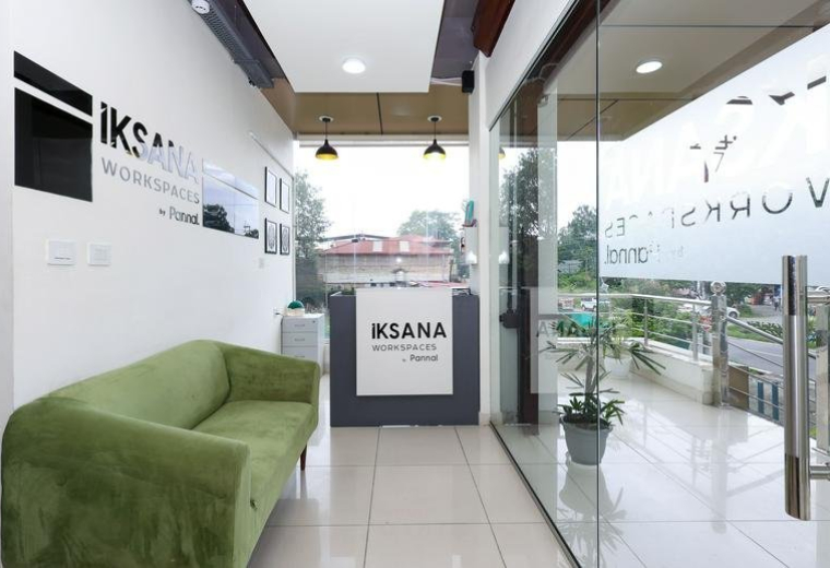Bright reception area at Anand Arcade, Canal Road, IT Park, Dehradun, India with a green sofa and glass entrance.