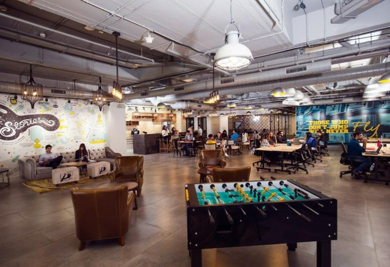 Spacious communal lounge at CoWrks Golf Course Road, Tower A, Paras Twin Towers with foosball and industrial lighting.