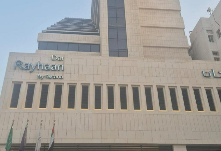 Exterior view of the tall, modern stone facade of the Dar Rayhaan by Rotana building.