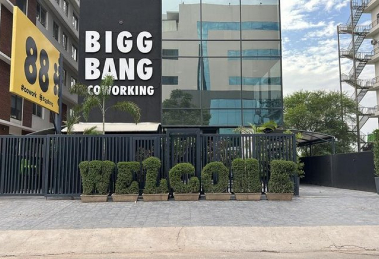 Exterior view of the Bigg Bang Coworking building with a large welcome sign made of hedges.