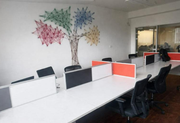 Open-plan workspace at Eleanor Technologies Pvt Ltd featuring a colorful string art tree mural and white desks.