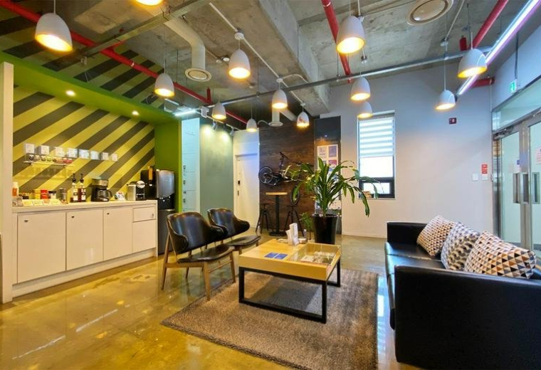 Spacious communal lounge at Nonhyun 237 Bldg. 3F / 4F with a coffee bar, striped feature wall, and modern seating.