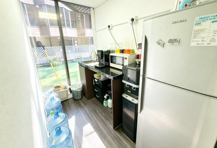Compact office pantry at New Mandarin Plaza with a coffee machine, microwave, and water dispensers near a large window.