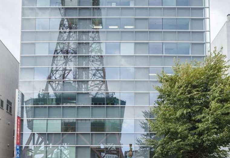 Modern glass exterior of the 9F Keiwa Odori Building 50 reflecting the Sapporo TV Tower.