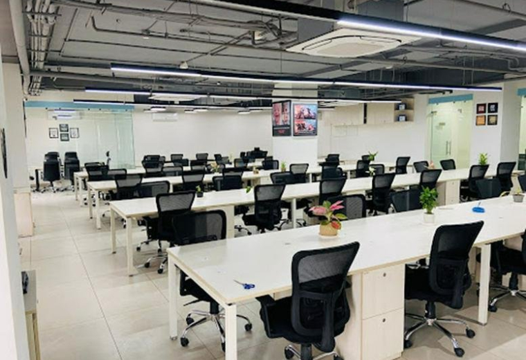 Spacious open-plan workspace at mall of jaipur, Gandhi Path Road with rows of white desks and black ergonomic chairs.