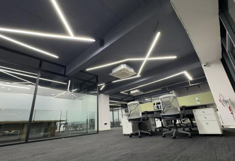 Spacious open-plan workspace at Marrichettu Road with modern linear ceiling lights and glass partitions.