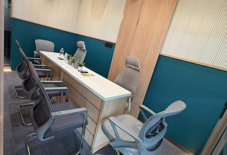 Wide-angle view of a professional meeting space with teal accents and linear lighting.