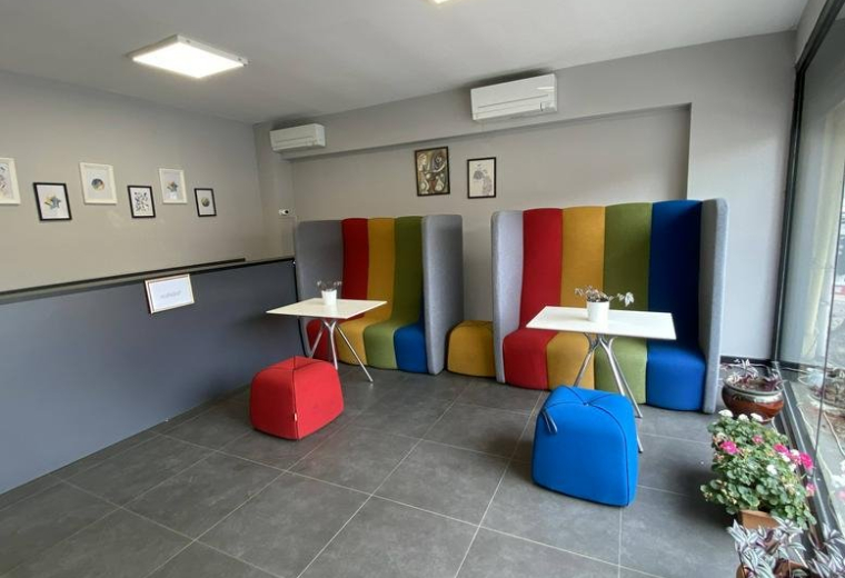 Bright coworking area with rainbow-colored high-back booths and a gray reception desk.