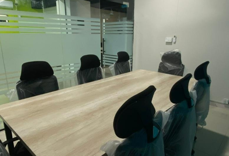 Meeting room at Talha Heights 2 with a light wood table, black chairs, and a white ceiling fan.