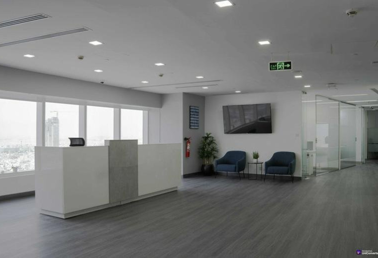 Modern white reception desk at Olaya Street with large windows and seating area.