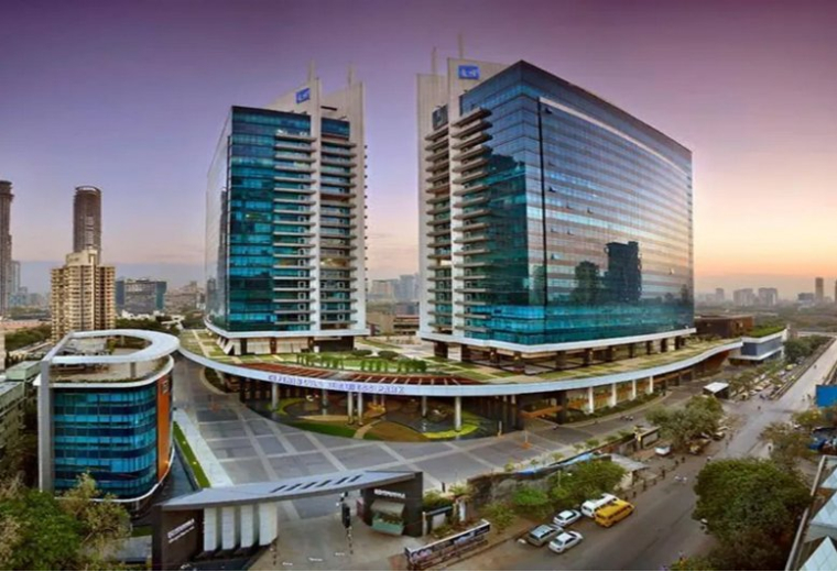 Wide-angle aerial shot of the twin office towers with a landscaped plaza at sunset.