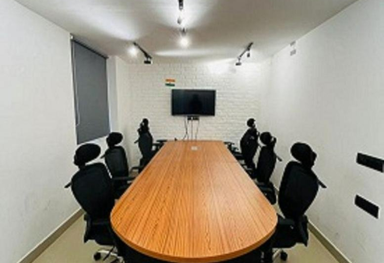 Meeting room at Plot 14, Yudhister Marg, ESIC Colony, C Scheme, Jaipur with a long wood-toned table and black chairs.
