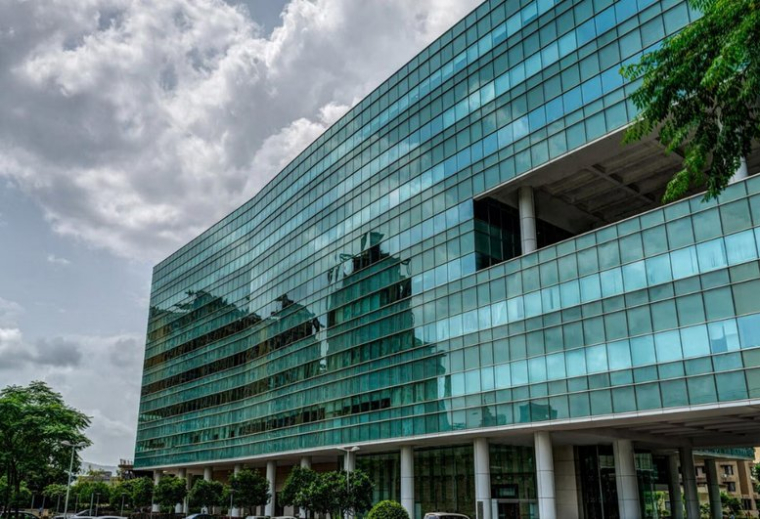 Exterior view of the glass-facade Redbrick Offices, Lodha Ithink building under a cloudy sky.