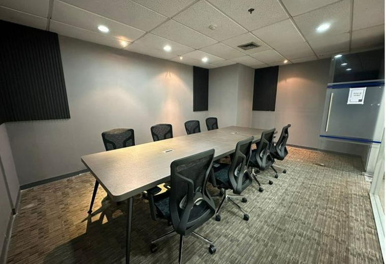 Spacious meeting room at Serm Mit Tower with a long grey table and black mesh chairs.
