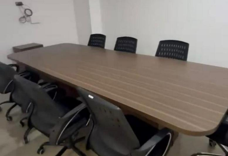 Meeting room at SOUTH-WING,, featuring a long wood-grain conference table and black mesh swivel chairs.
