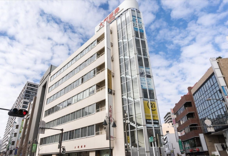 Exterior view of the glass-fronted Success Hon-Atsugi Building on a city corner.