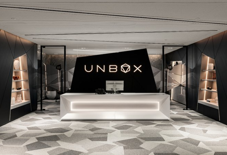Futuristic white reception desk at unbox featuring a black angular backdrop.