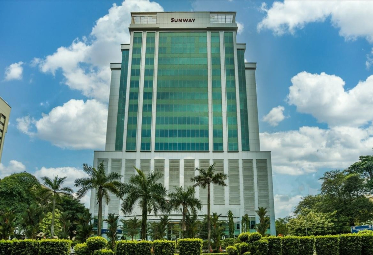 Exterior view of the glass-facade Wisma Sunway building against a blue sky.
