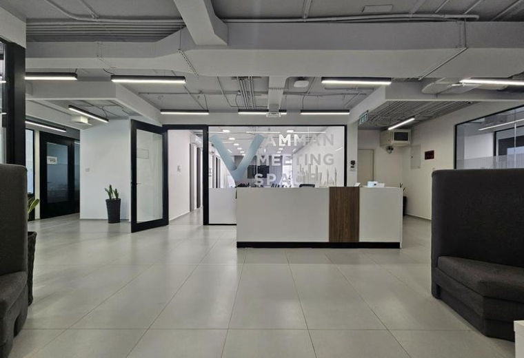 Reception area with a modern white desk and glass partitioned doors.