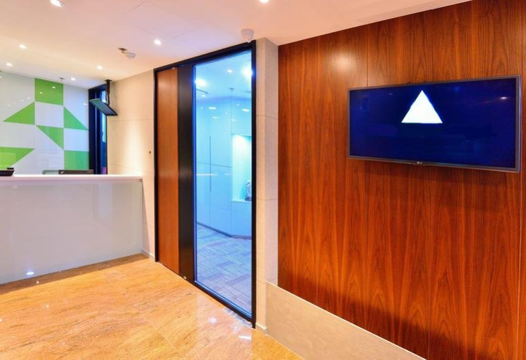 Bright reception area at Woon Lee Commercial Building with wood paneling and a digital display screen.