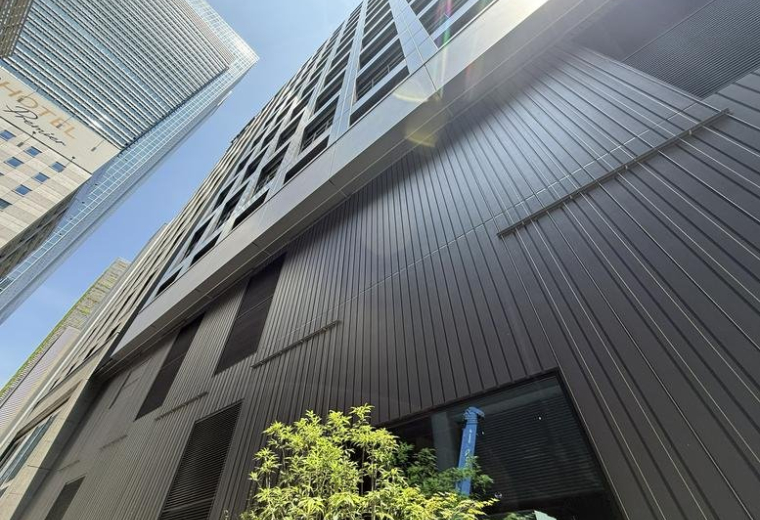 Low-angle exterior view of the modern glass and steel facade of the Yaesu Daibiru Building.