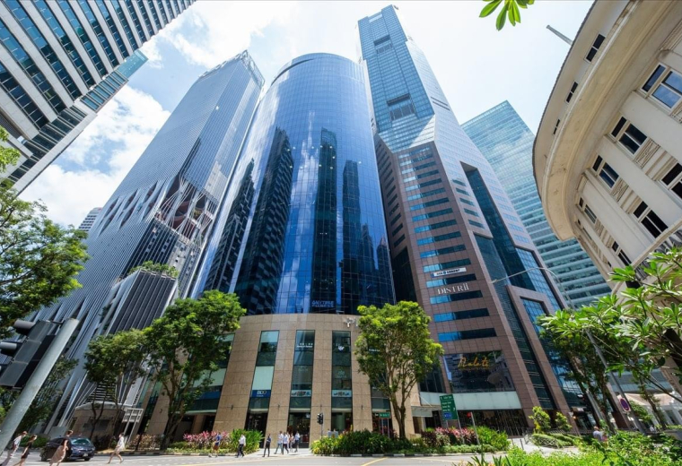 A low-angle view of the towering glass facade of the PLUS Building in Singapore.