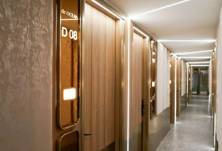 Modern corridor at Mai Tak Industrial Building with warm wooden doors and linear LED lighting.