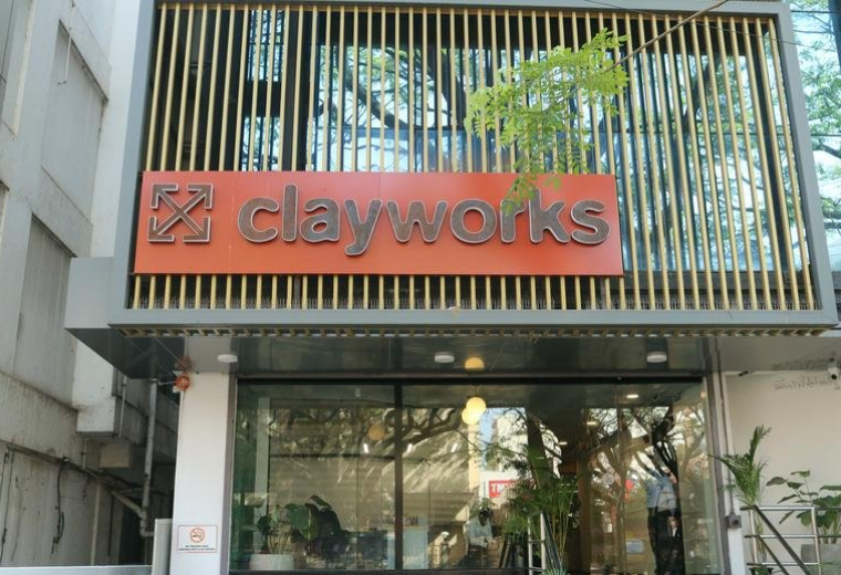 Entrance of the building with Clayworks sign and greenery.
