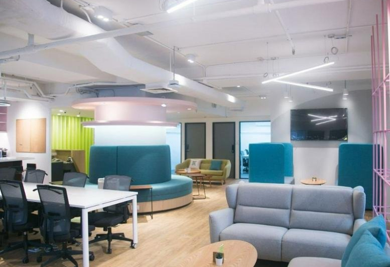 Spacious lounge at Sunbeam Centre with colourful teal seating, a light wood floor, and warm overhead lighting.