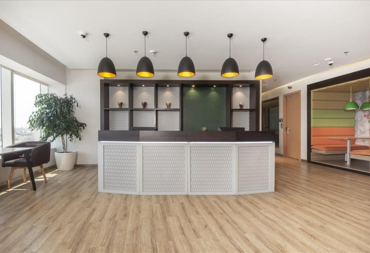 Reception area featuring a white front desk, wooden floors, and modern pendant lighting.