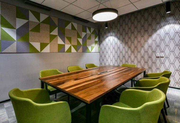 Modern meeting room at The Empire Tower with a large wooden table and lime green armchairs.