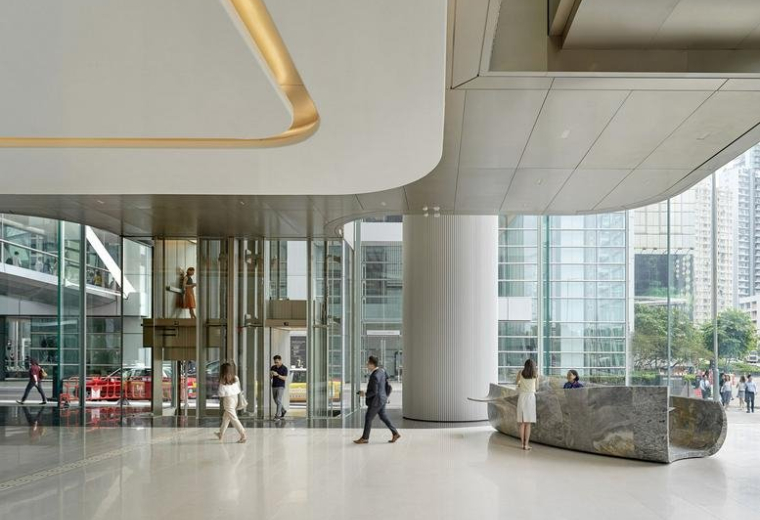 A bright, high-ceilinged building lobby with marble floors and floor-to-ceiling windows.