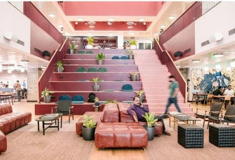 Spacious multi-level atrium at Vi-John Tower 393 with tiered seating, plants, and a grand staircase.