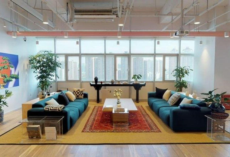 Spacious communal lounge at Waterfront Park with two large blue sofas, plants, and a colorful feature painting.