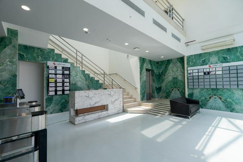 Sleek reception area at طريق خريص الفرعي featuring a marble desk and vibrant green marble-patterned walls.