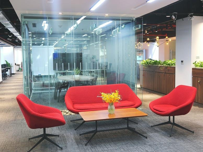 Modern lounge at 1 Phố Lương Yên with vibrant red seating and a glass-walled meeting room.