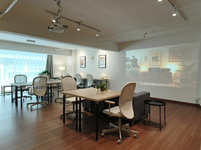 Spacious open-plan common area at Menara Majestic with desks and a large projection screen.