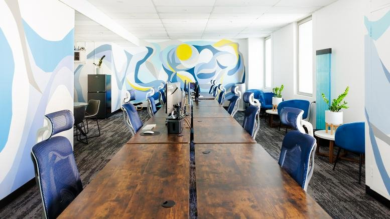 Spacious open-plan workspace at 117, King William Street featuring wooden desks and a vibrant blue mural.