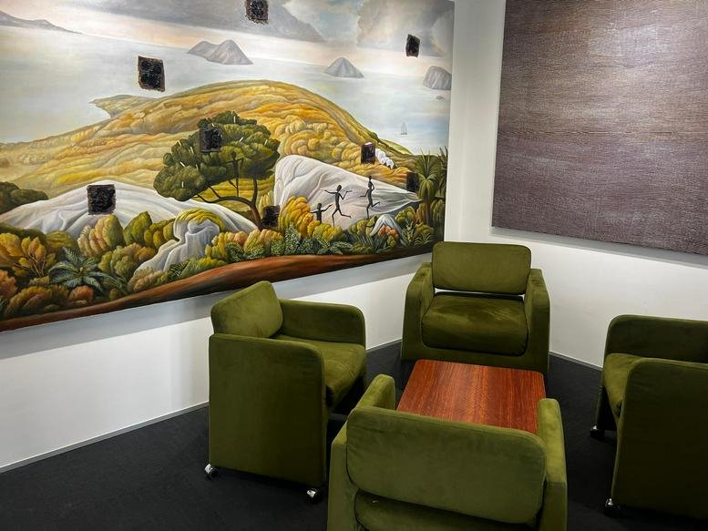 Interior lounge area with green chairs and a mural wall at 140, Bourke Street, Melbourne.