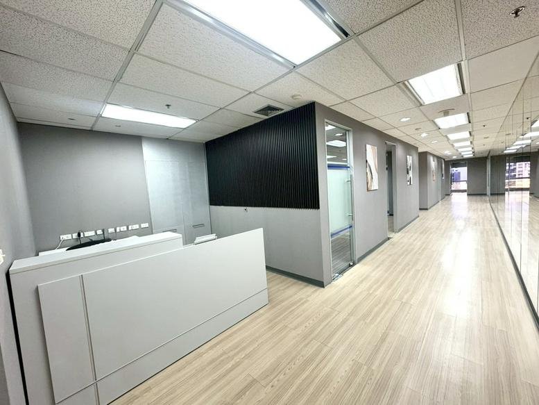 Spacious reception area at 159 Sukhumvit 21 Rd with a modern white desk and wood-style flooring.