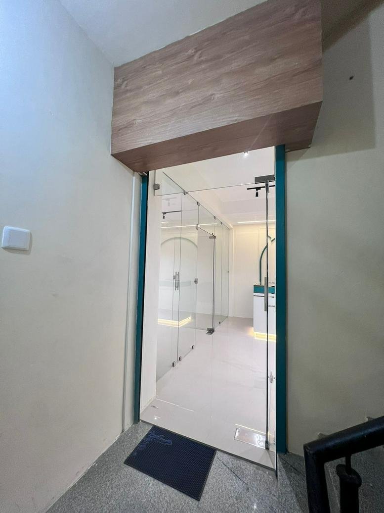 Modern glass entrance to the 163B, Venkatachalam Chetty Street office with wood-paneled header.