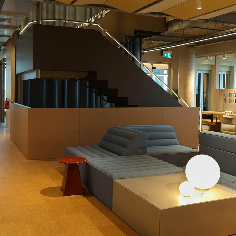Modern lounge area at 189, Toorak Road with tiered blue seating and a decorative staircase.