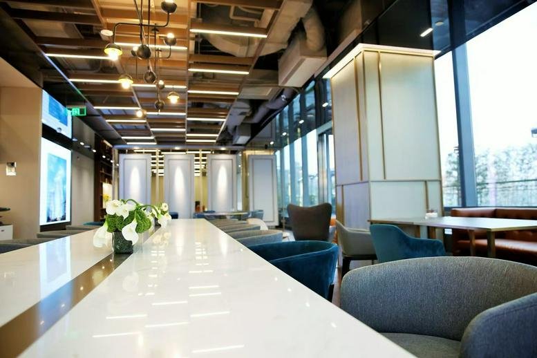 Spacious lounge with contemporary blue armchairs and views of the Shanghai skyline.