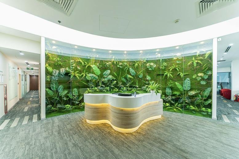 Modern reception area at 19, Đường Cao Thắng featuring a curved white desk and vibrant green leaf mural.