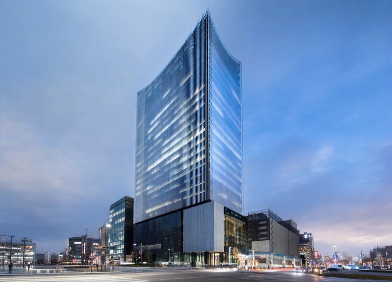 Exterior view of the modern glass facade Museum Tower Kyobashi at dusk.
