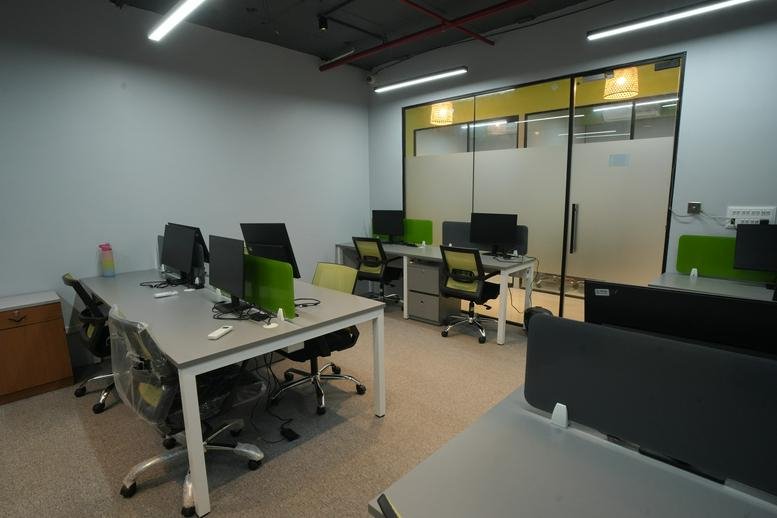 Spacious open-plan workspace at Trinity Towers with modern desks and green privacy dividers.